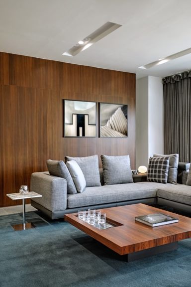Furnished living space with a grey modular sofa, low wooden coffee table and timber-panelled wall